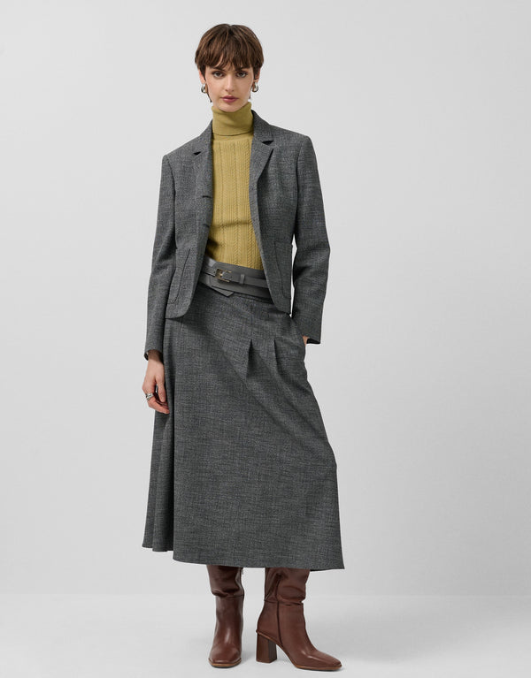 Woman wearing a gray coat, green sweater, and brown boots on a white background
