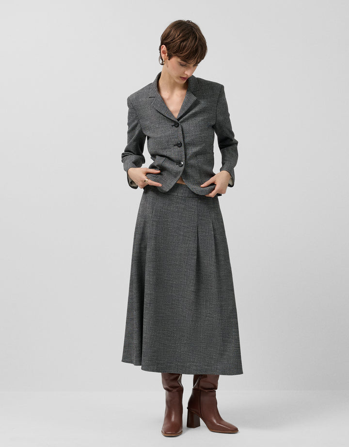 Woman wearing a gray coat and skirt set on a white background