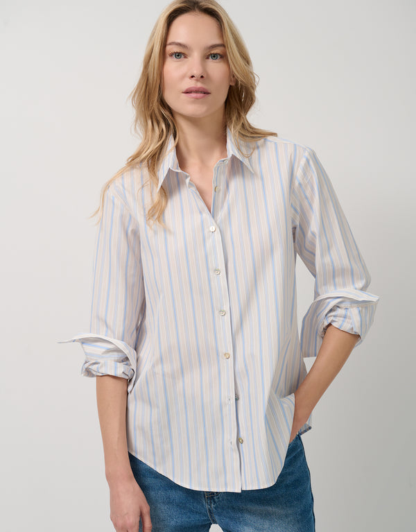 Woman wearing a striped shirt and jeans on a plain background