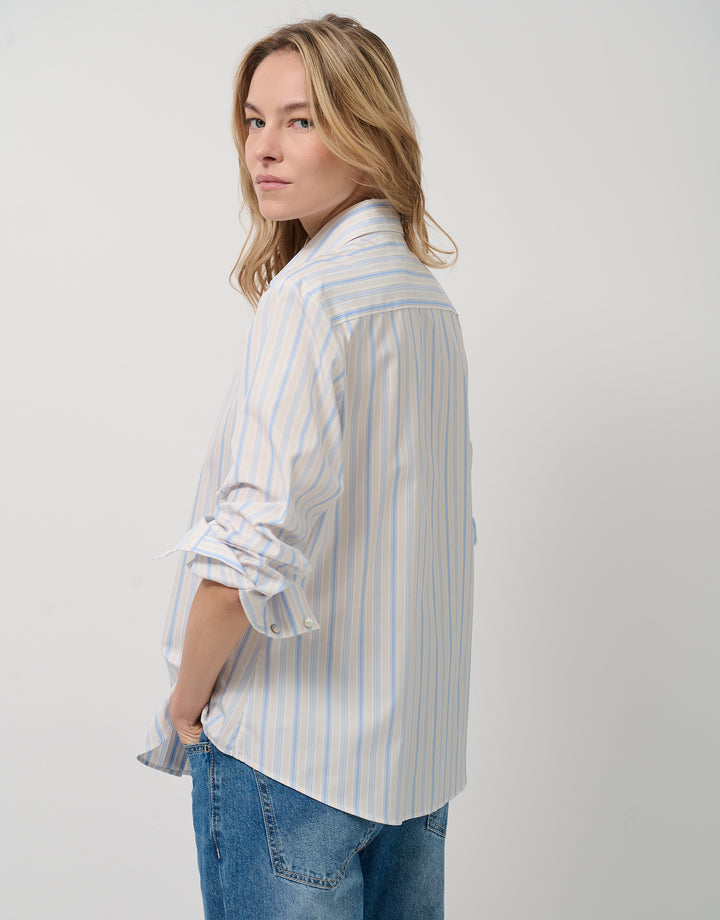Woman wearing a striped shirt and jeans on a plain background