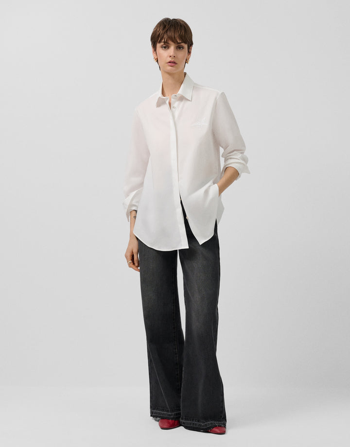 Woman wearing a white blouse and black pants on a light gray background