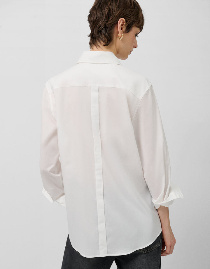 Person wearing a white blouse with a plain background