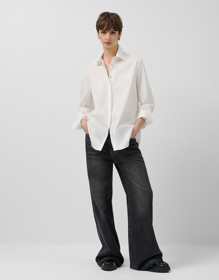 Person wearing a white shirt and black pants on a plain background