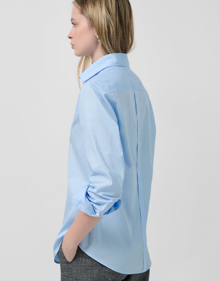 Woman wearing a light blue shirt against a plain background