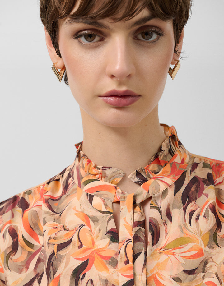 Close-up of a person wearing a patterned shirt with a plain background