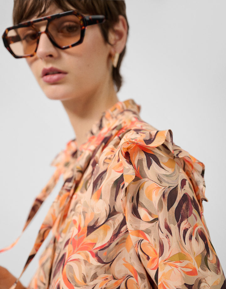 Person wearing a patterned shirt with a neutral background