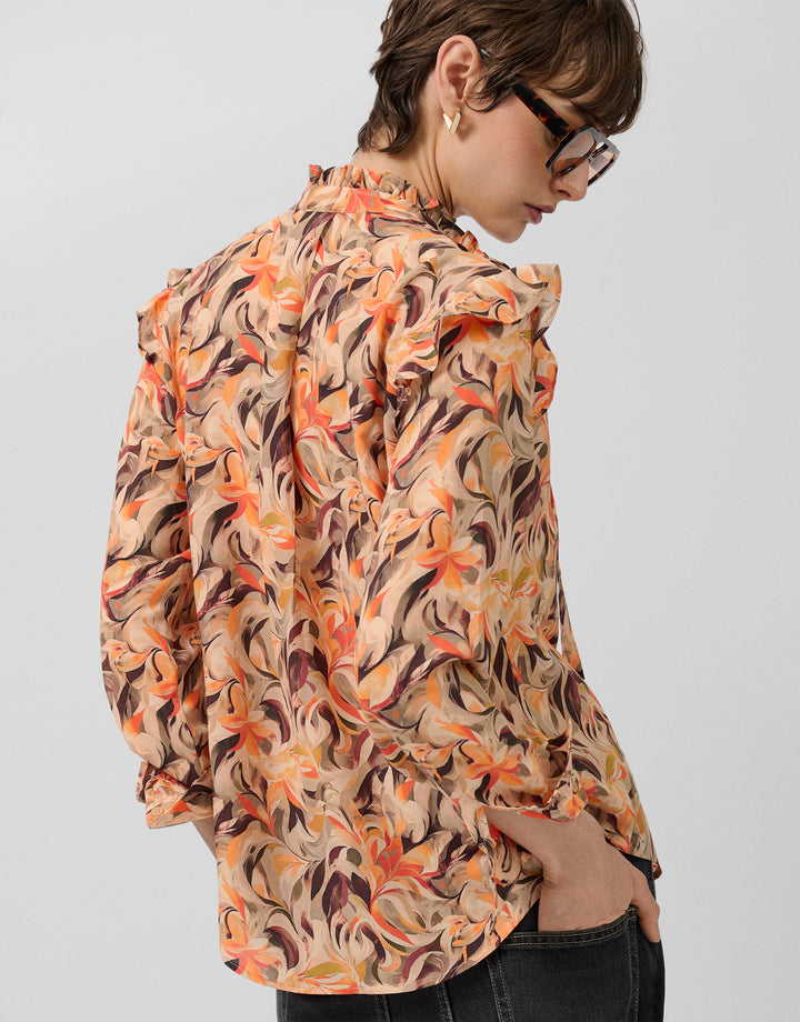 Person wearing a floral patterned blouse on a plain background