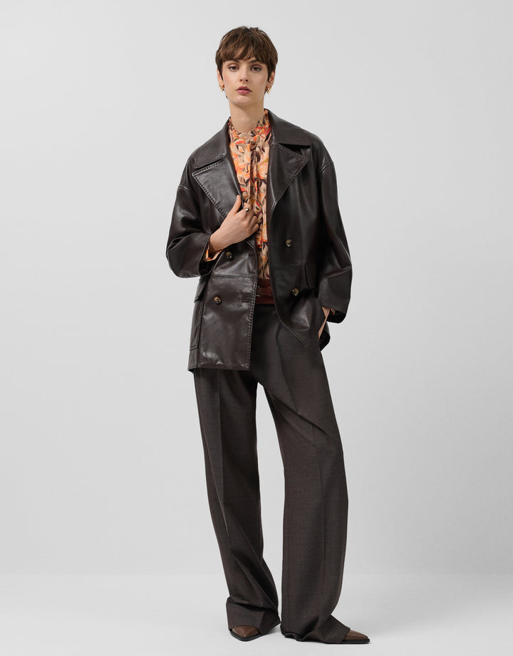 Person wearing a black leather outfit on a plain background