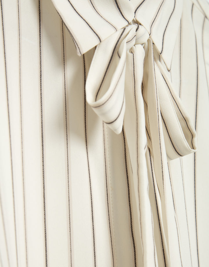 Close-up of a white robe with a tie detail on a white background