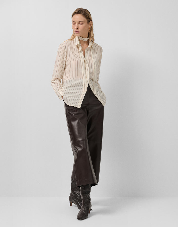 Woman wearing a striped shirt and leather pants on a white background