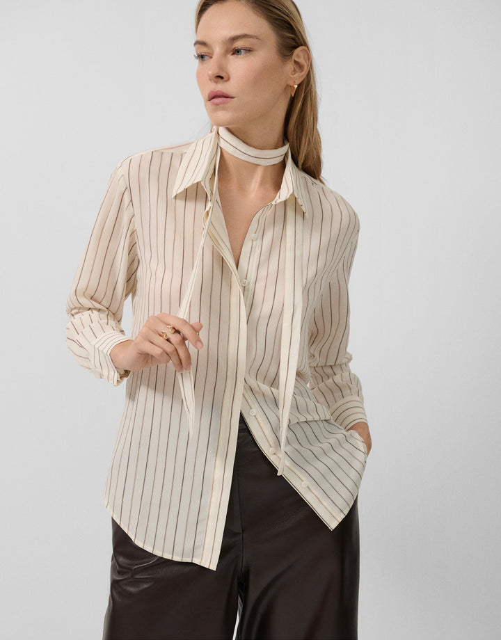 Woman wearing a striped shirt with a white collar against a light background