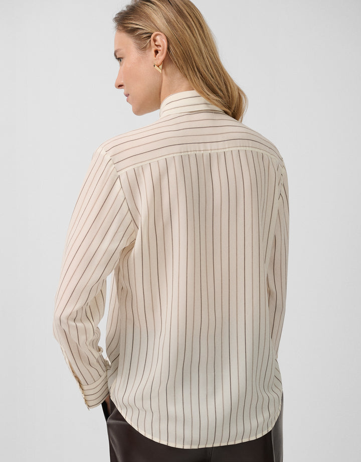 Woman wearing a beige ribbed long-sleeve shirt on a light gray background