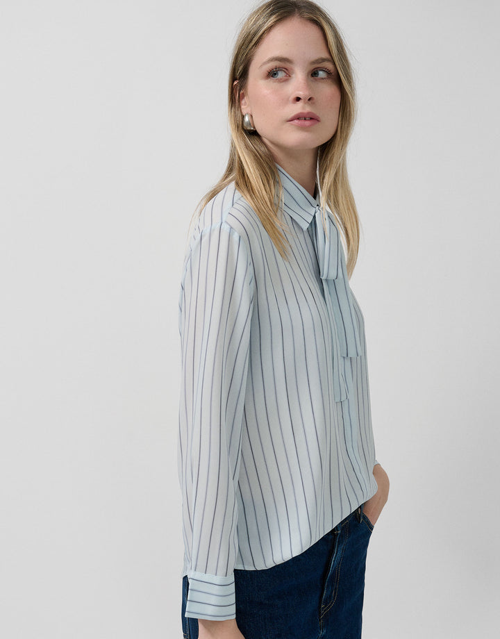 Woman wearing a light blue striped shirt against a white background