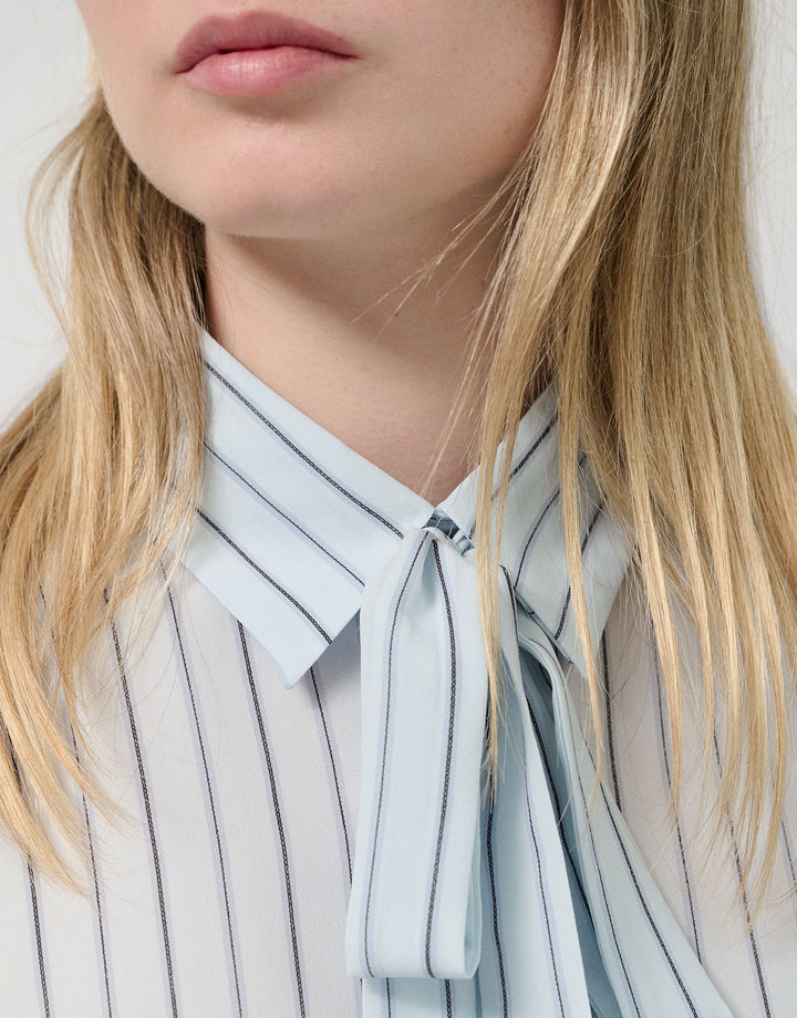 Close-up of a person wearing a striped shirt with a bow tie against a white background