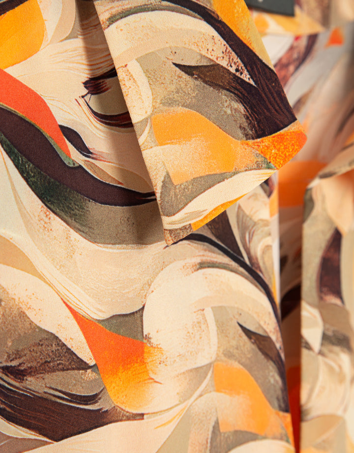 Close-up of fabric with abstract pattern in orange, brown, and beige.