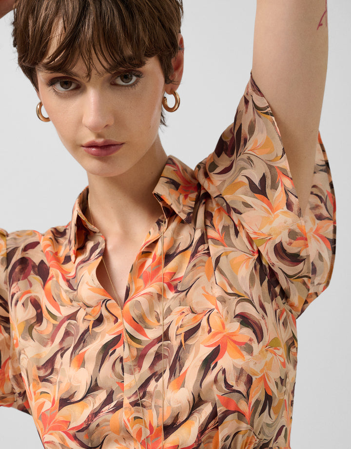 Woman wearing a patterned shirt with a neutral background