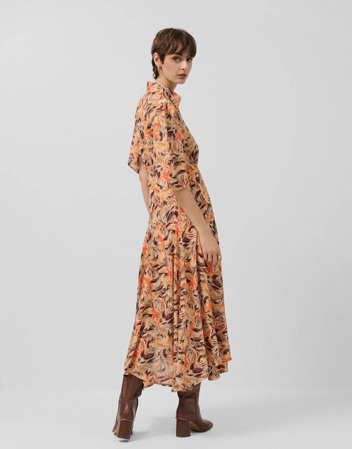 Woman wearing a patterned dress with long sleeves on a plain background