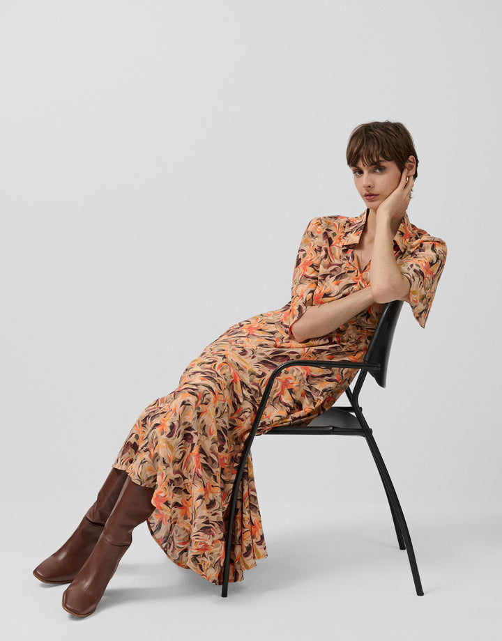 Woman in a floral dress sitting on a chair against a white background