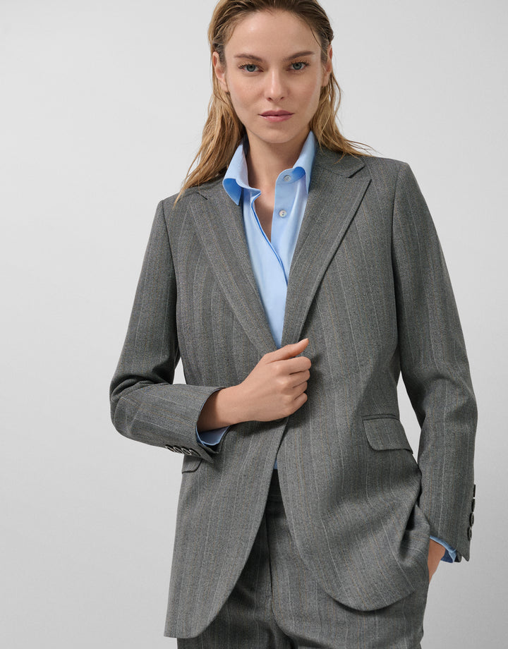 Woman wearing a gray suit with a light blue shirt on a white background