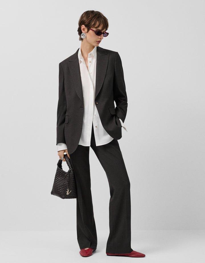Person wearing a black suit with a white shirt and red shoes on a white background