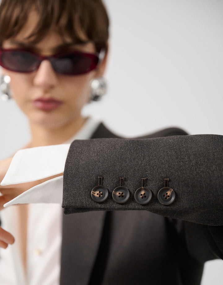 Close-up of a dark gray suit jacket with buttons, blurred background