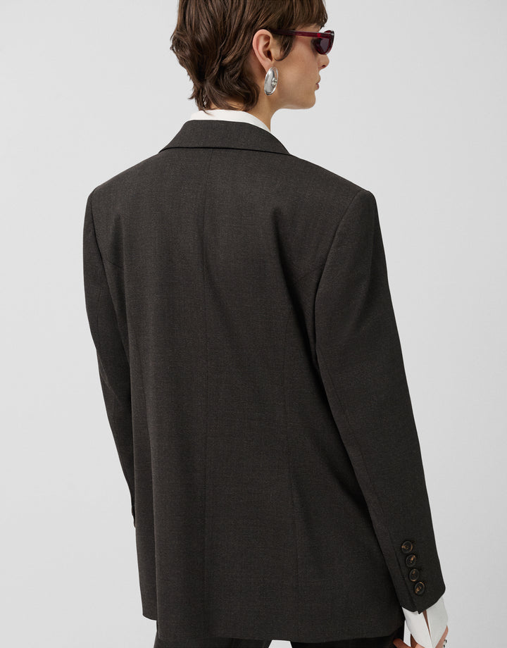Person wearing a dark gray blazer on a light gray background