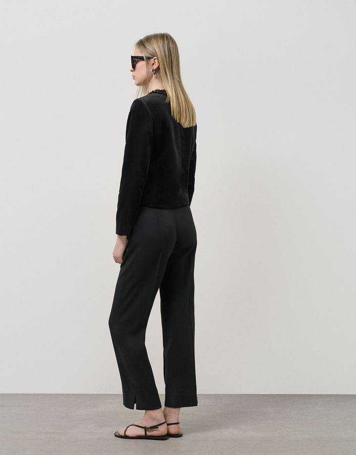 Woman wearing a black outfit with sunglasses on a plain background