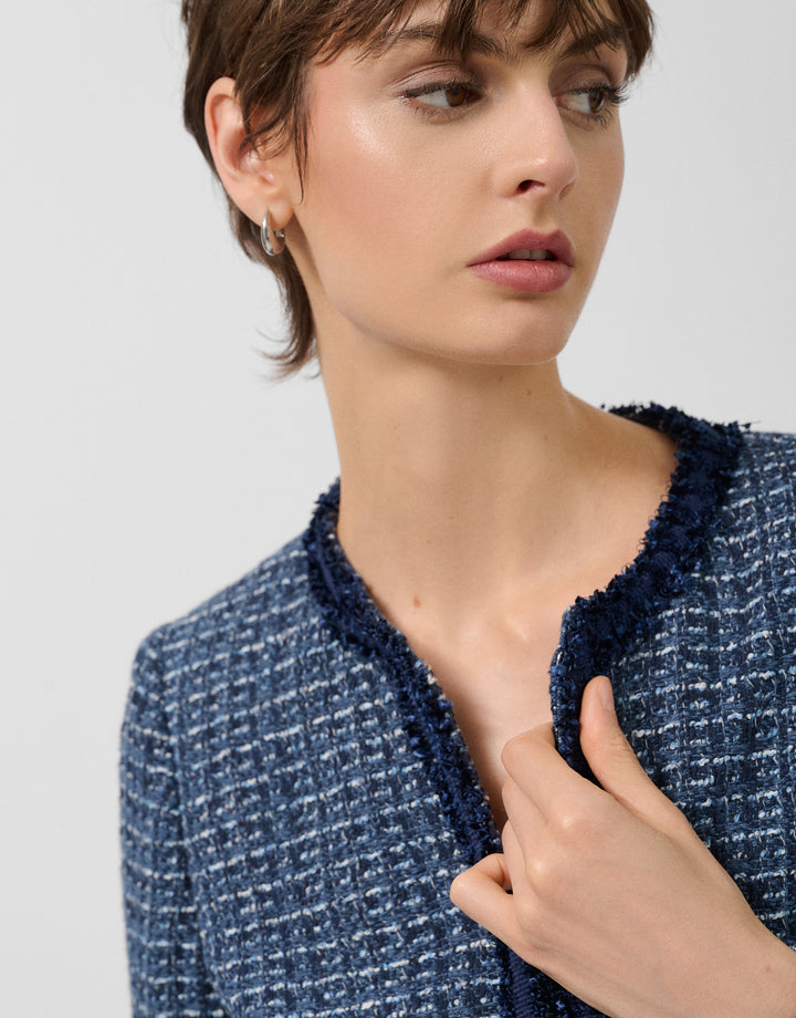 Woman wearing a blue textured jacket against a light background