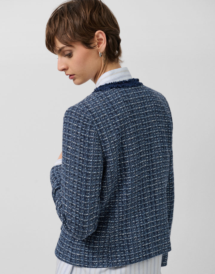 Woman wearing a blue tweed jacket on a light gray background