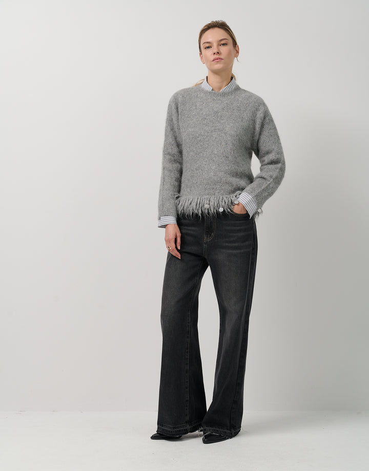 Person wearing a gray sweater and black pants on a white background