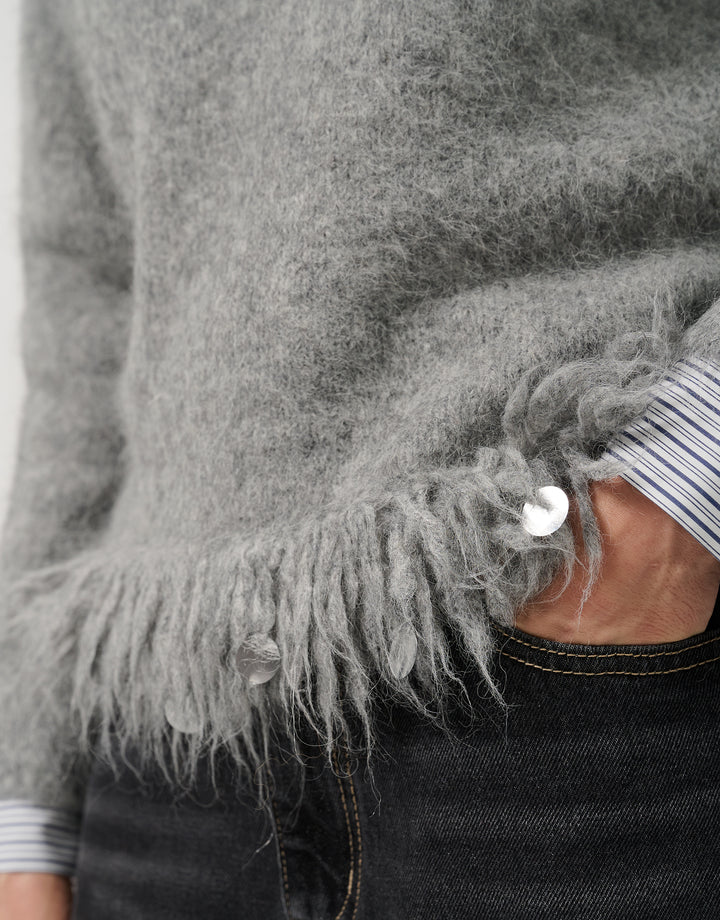 Close-up of a gray sweater with frayed edges and a person wearing it.