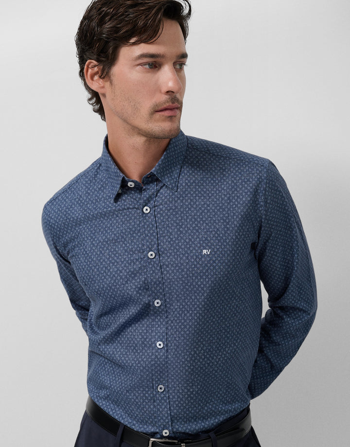 Man wearing a blue patterned shirt on a gray background