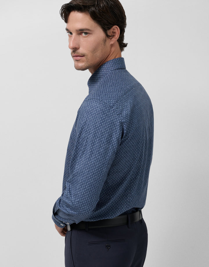 Man wearing a blue patterned shirt against a light gray background