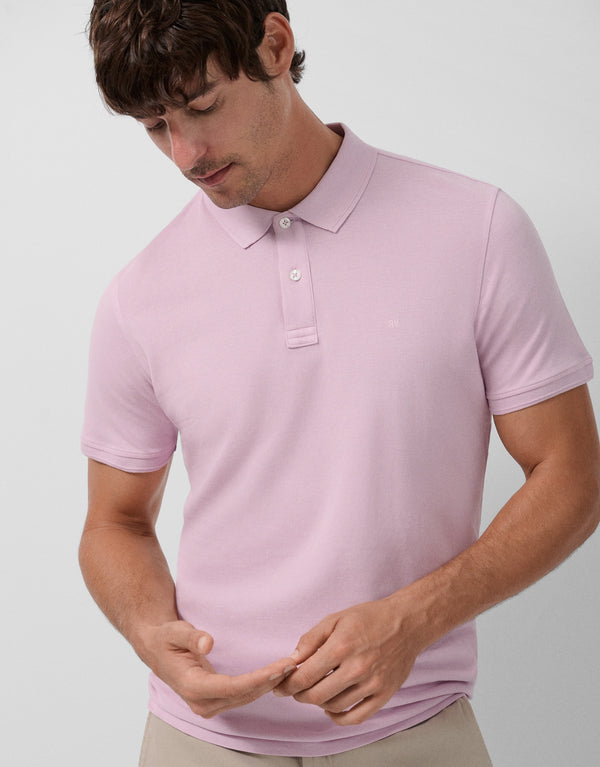 Man wearing a light pink polo shirt against a plain background