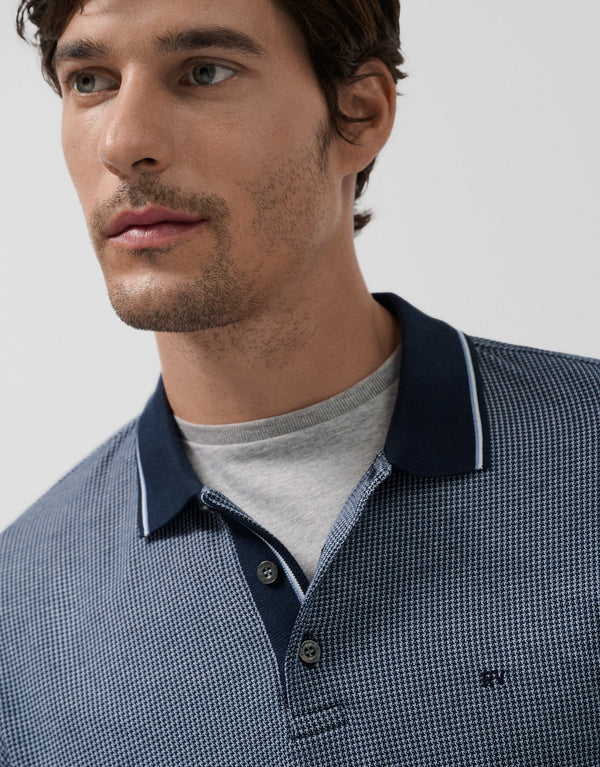 Man wearing a blue checkered polo shirt with a gray collar against a light gray background