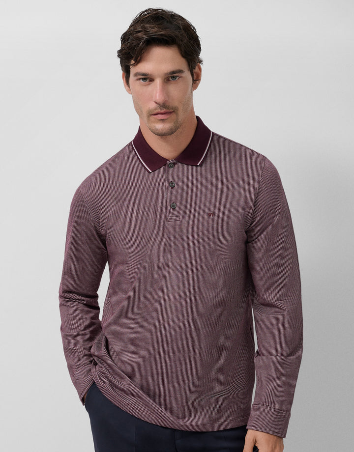 Man wearing a maroon long-sleeve polo shirt against a light gray background