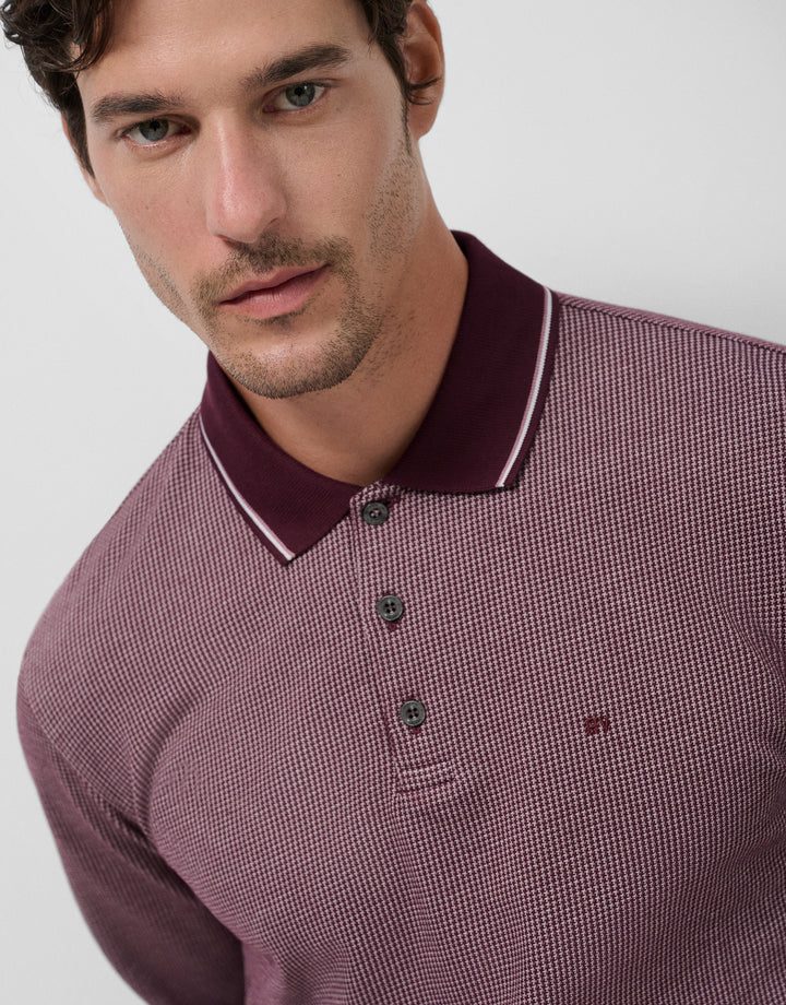 Man wearing a maroon checkered polo shirt with a white background