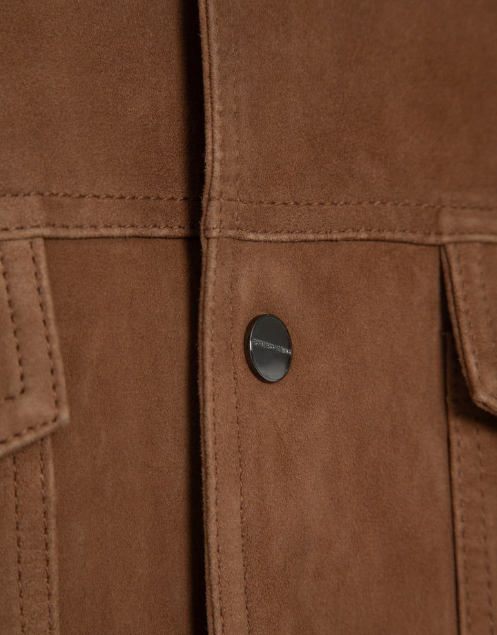 Close-up of a brown jacket with a button featuring a brand logo.