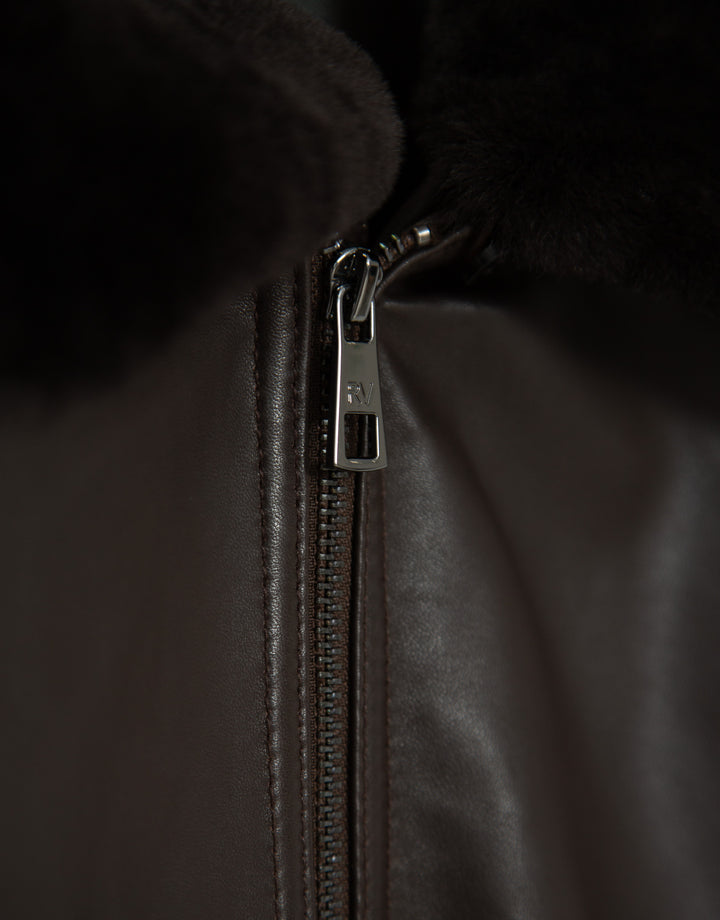 Close-up of a zipper on a dark jacket with a brand logo.