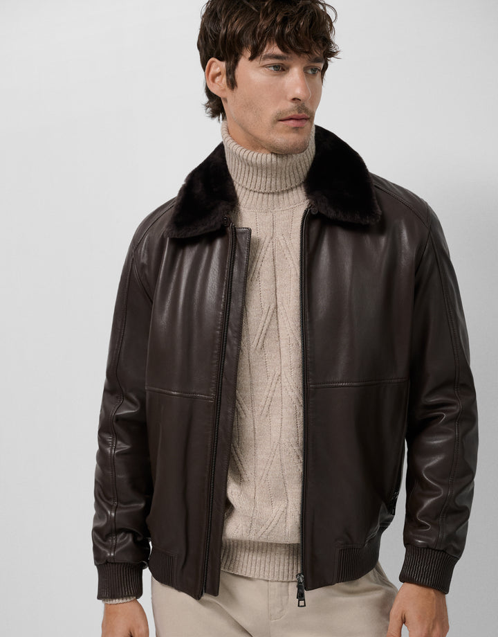 Man wearing a brown leather jacket with a fur collar on a white background