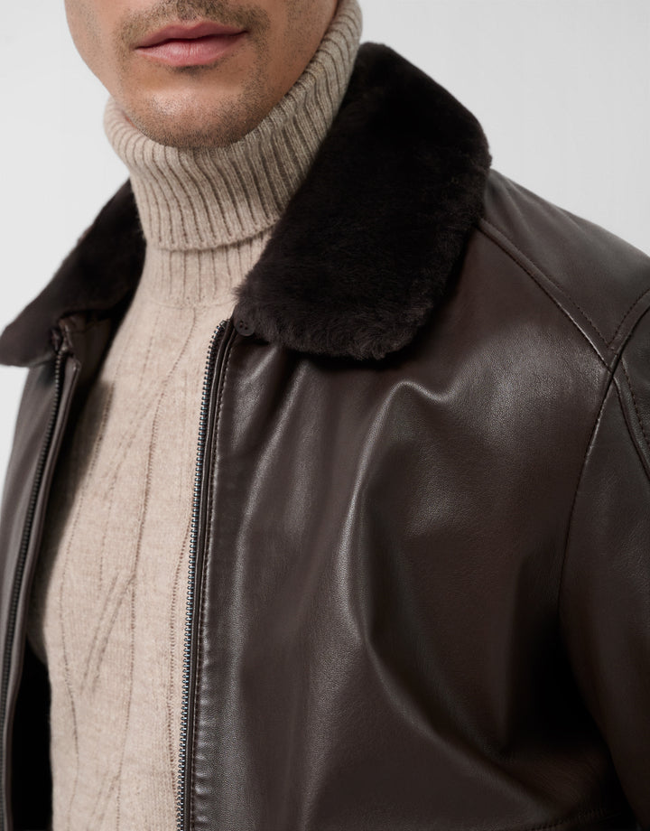 Brown leather jacket with fur collar worn by a person, on a light gray background