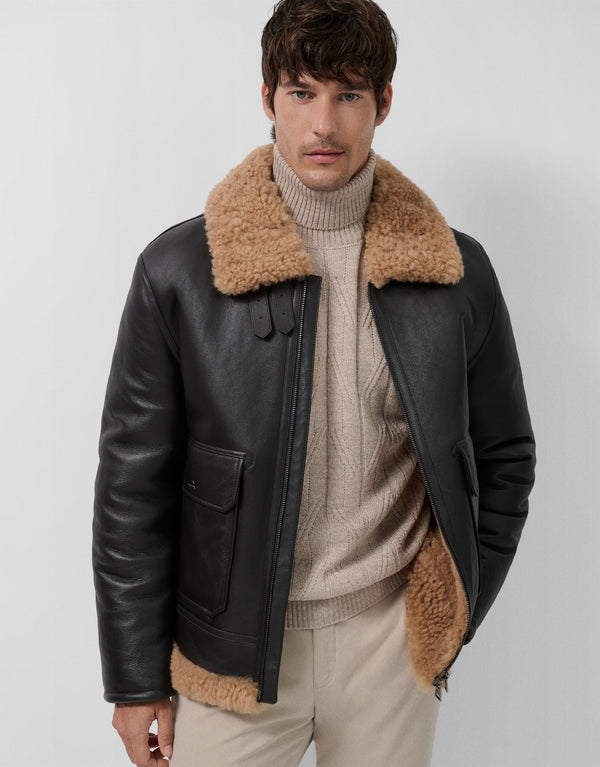 Man wearing a black leather jacket with brown fur collar and cuffs on a white background
