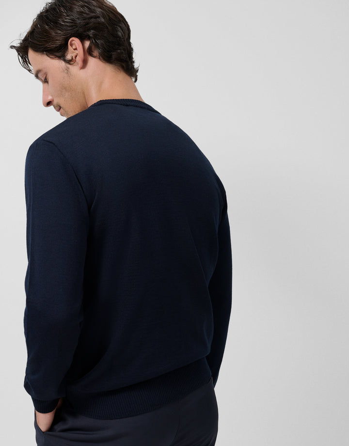 Man wearing a navy blue sweater against a light gray background