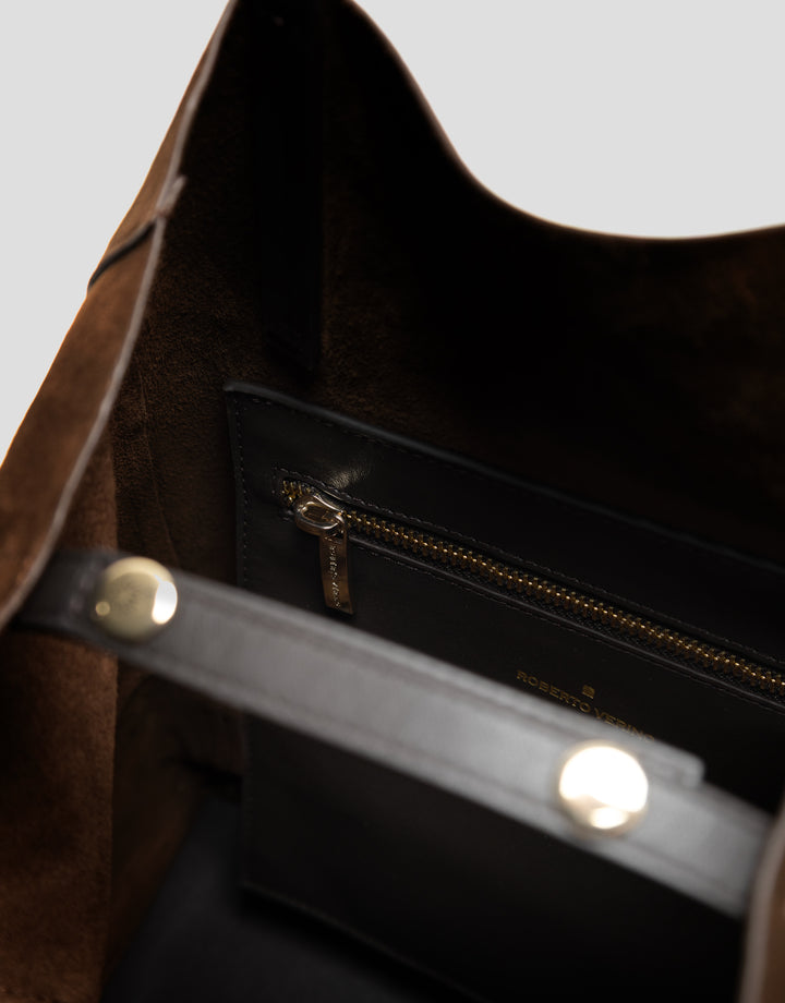 Close-up of a brown leather bag with gold zipper and hardware.