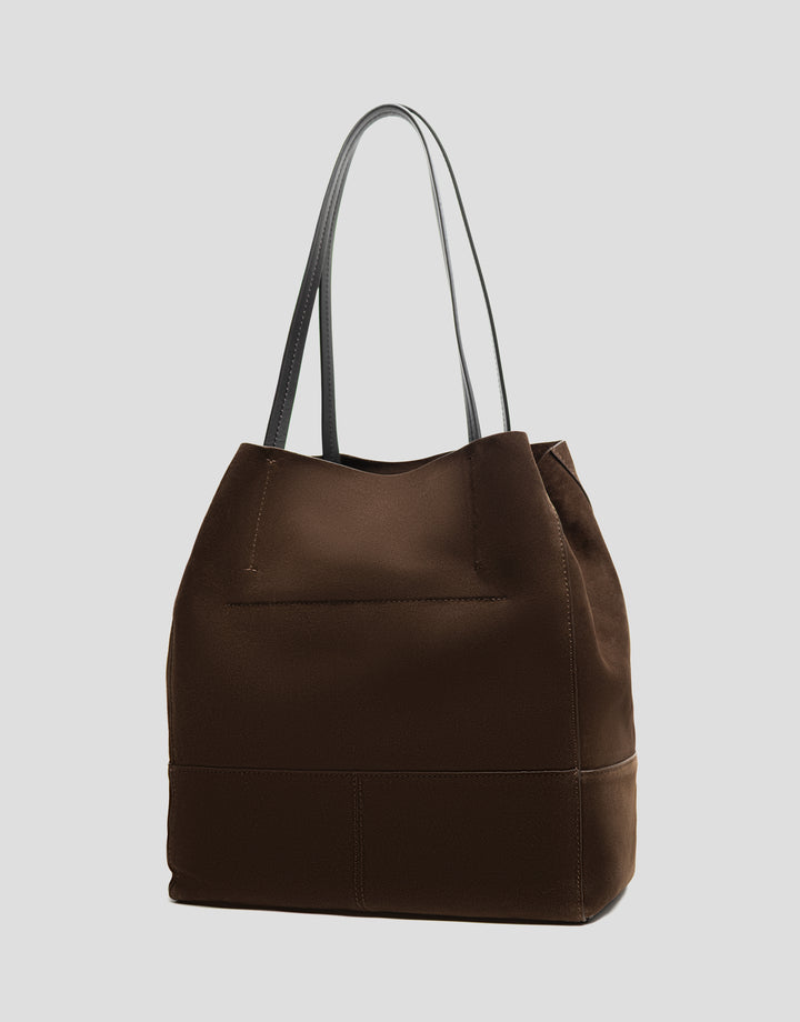Brown leather tote bag with black handles on a light gray background