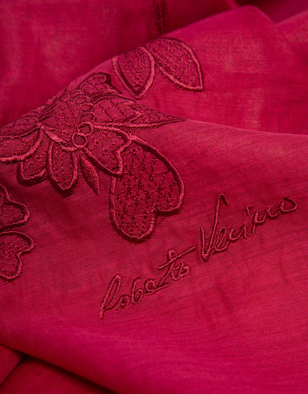 Close-up of a red fabric with embroidered floral design and 'Roberto Verino' branding.