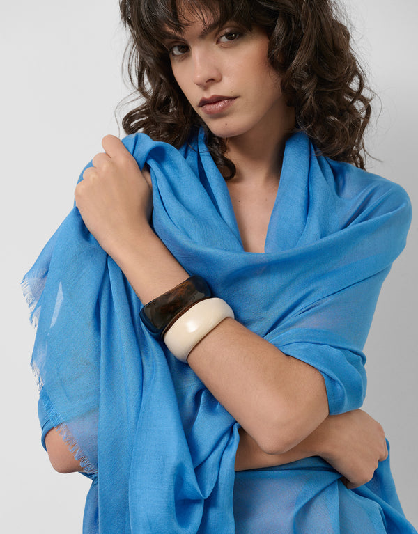 Woman wearing a blue scarf with a plain background