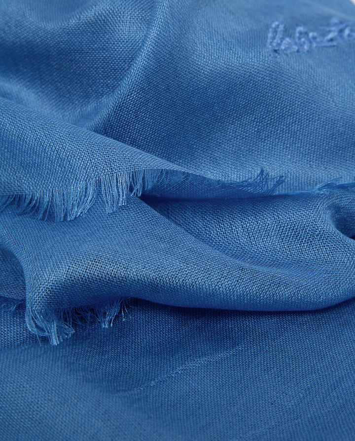 Close-up of blue fabric with a brand label on a blue background