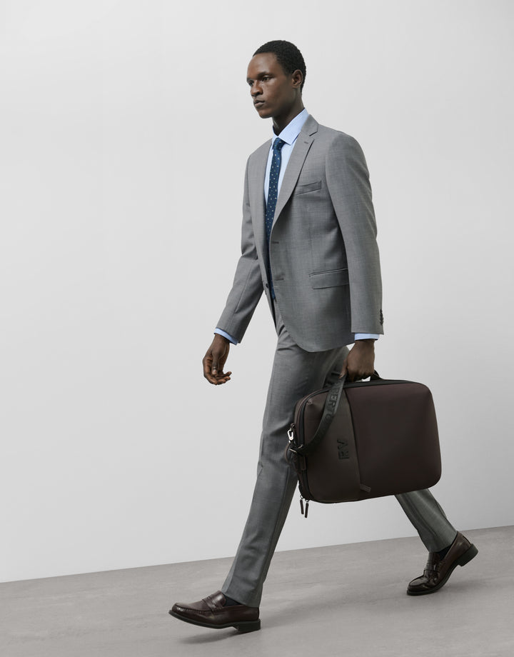 Man in a gray suit walking with a brown briefcase against a white background
