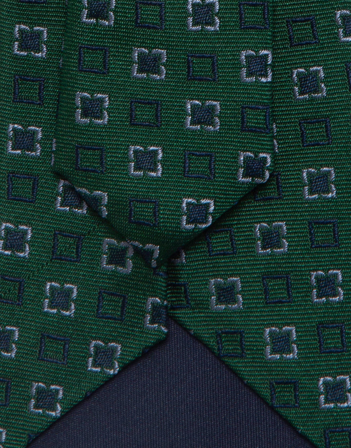 Close-up of a green tie with a geometric pattern on a matching fabric background